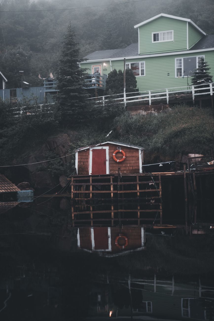Scandinavian wooden cabin overlooking reflective cold fjord
